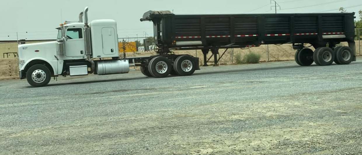 Peterbilt tractor unit 827 hitched to a black transfer trailer, staged in the yard